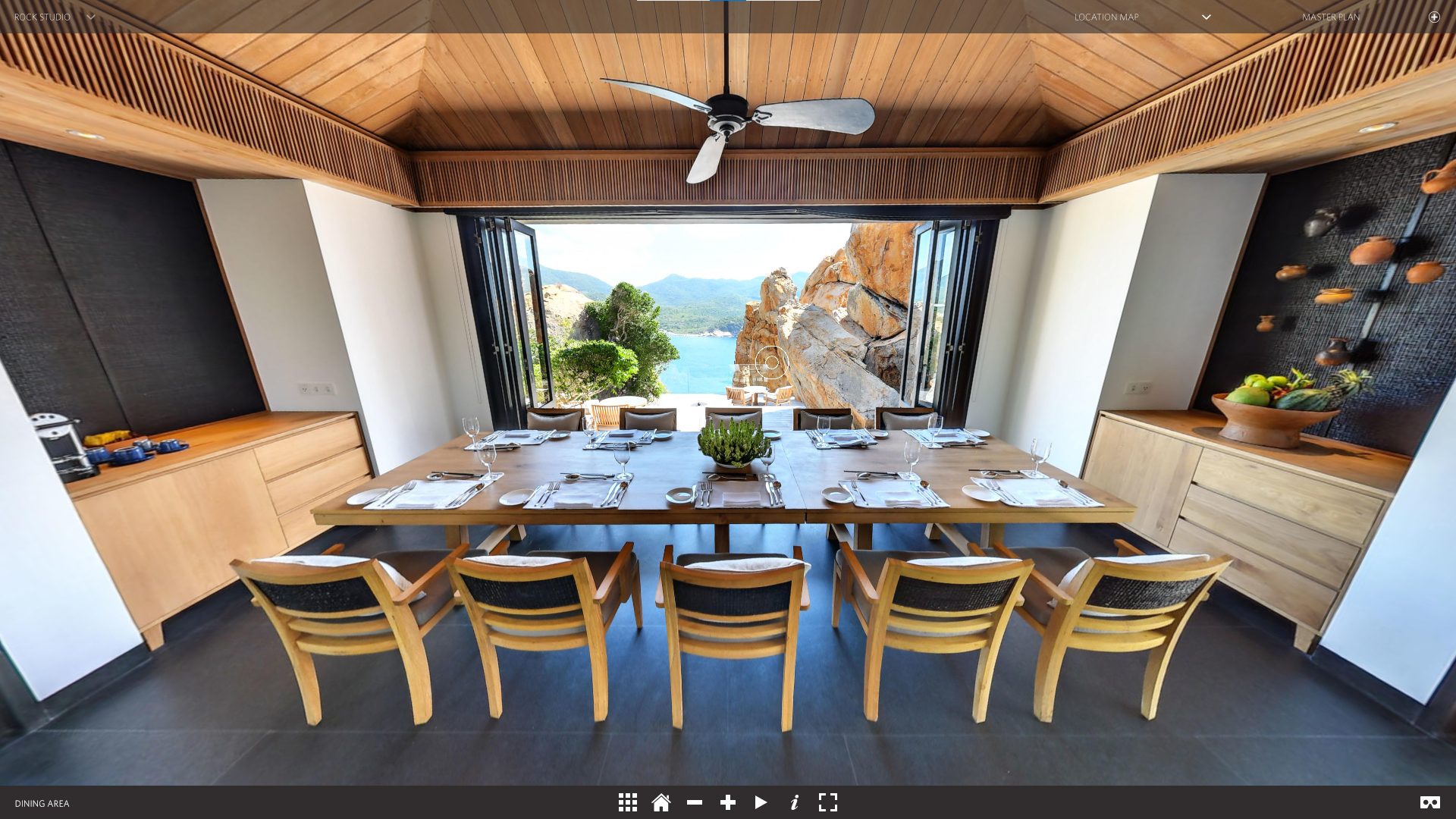 360 photo of a living room sala, with a gorgeous view on the cliff and sea behind. Wooden decor and dining table.